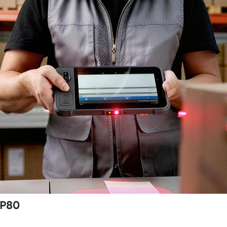 A warehouse worker holds the CedaGlo P80 with both hands and scans a carton label at a packing bench